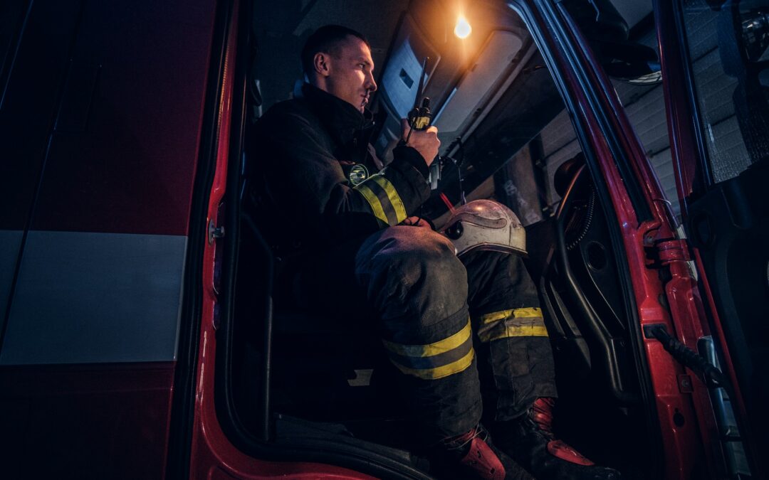 Fireman in a protective uniform sitting in the fire truck and talking on the radio