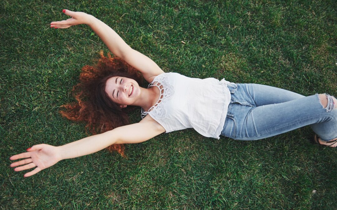 Relaxing girl with red, lying on the grass. Woman relaxes outdoors
